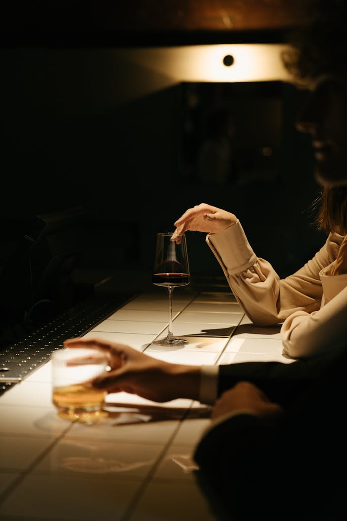 Two people enjoying drinks at a dimly lit bar counter, creating an intimate atmosphere.